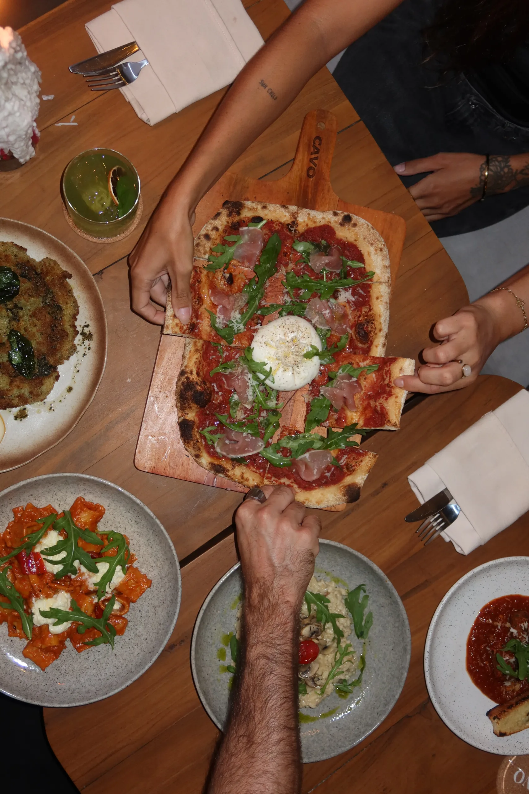 Table of shared Italian dishes including pizza, pasta and antipasti at CAVO