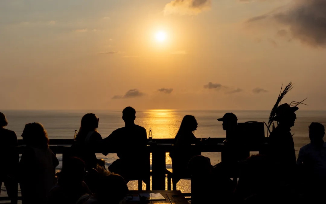 Silhouettes of people watching the sun set over the Indian Ocean from a clifftop bar in Uluwatu, Bali