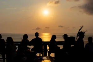 Silhouettes of people watching the sun set over the Indian Ocean from a clifftop bar in Uluwatu, Bali