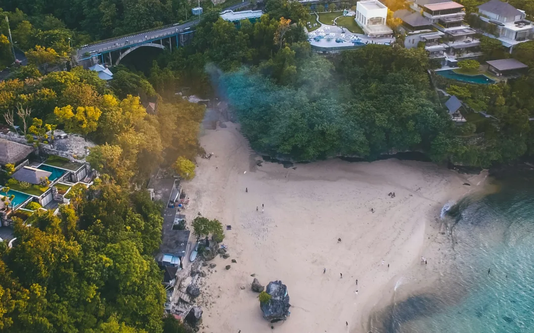 Aerial view of Padang Padang Beach in Uluwatu, Bali, with white sand, turquoise water, the Padang Padang bridge and clifftop villas