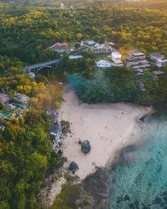 Aerial view of Padang Padang Beach in Uluwatu, Bali, with white sand, turquoise water, the Padang Padang bridge and clifftop villas