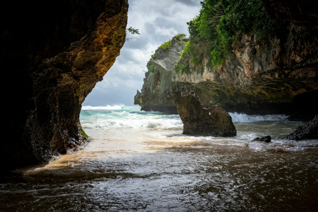 View from inside the Suluban cave in Uluwatu, Bali, looking out at waves breaking between limestone cliffs